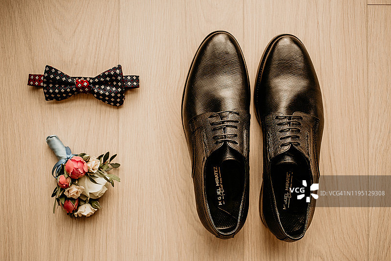 特写的现代新郎配件。黑色领结，皮鞋和花朵胸花在乡村背景。设置为正式风格的穿着孤立在白色背景图片素材