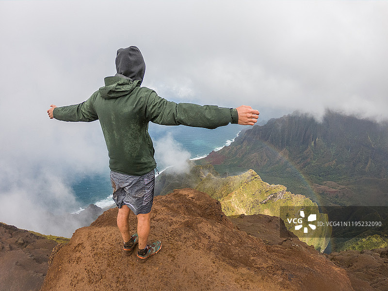 美国夏威夷，一个年轻人站在山顶，眺望着张开双臂的大海图片素材