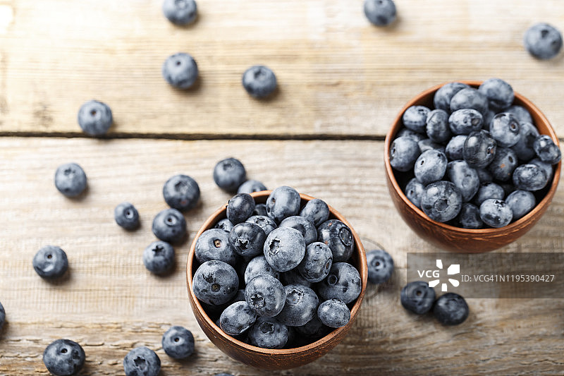 成熟的蓝莓放在粘土盘子里，棕色的木制背景。图片素材