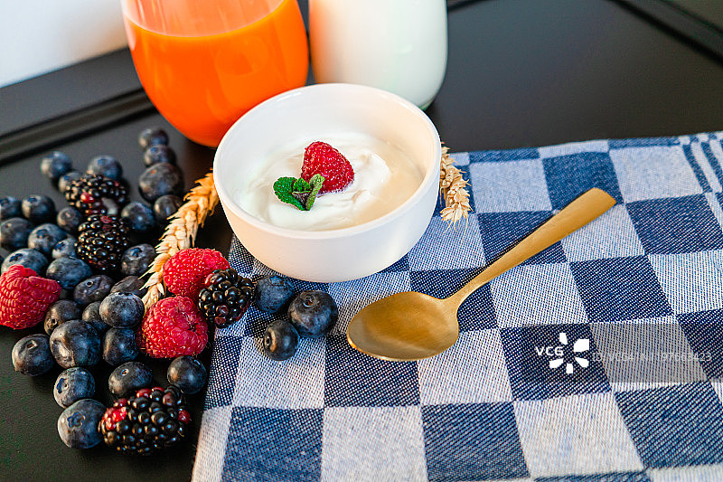 酸奶和新鲜的蓝莓，树莓放在木桌上。健康饮食图片素材