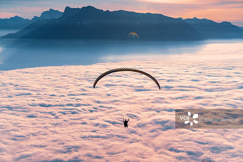 一个滑翔伞的剪影飞行在云地毯在日落，Gaisberg，萨尔茨堡，奥地利图片素材