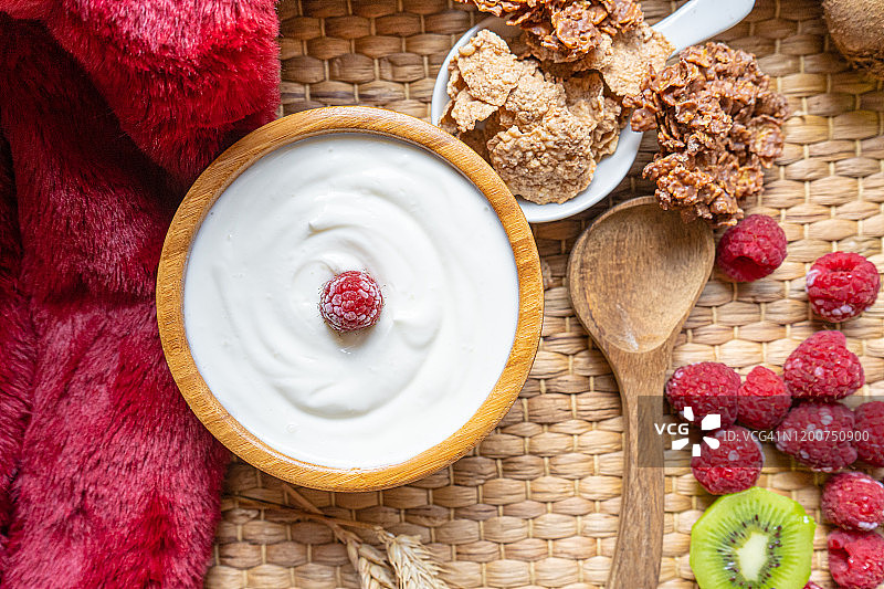 希腊酸奶碗和勺子，健康的早餐与新鲜的希腊酸奶，麦片和浆果的背景图片素材