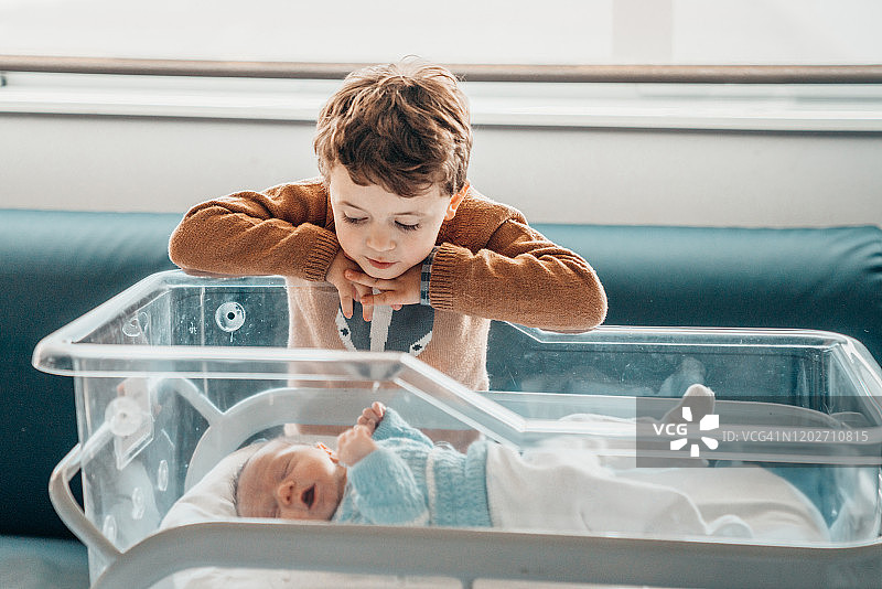 兄弟们在医院的婴儿床上看着刚出生的弟弟图片素材
