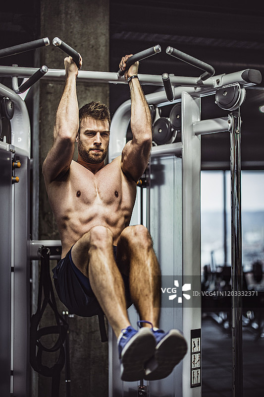 肌肉健美的人在健身房的机器上锻炼腹部肌肉。图片素材