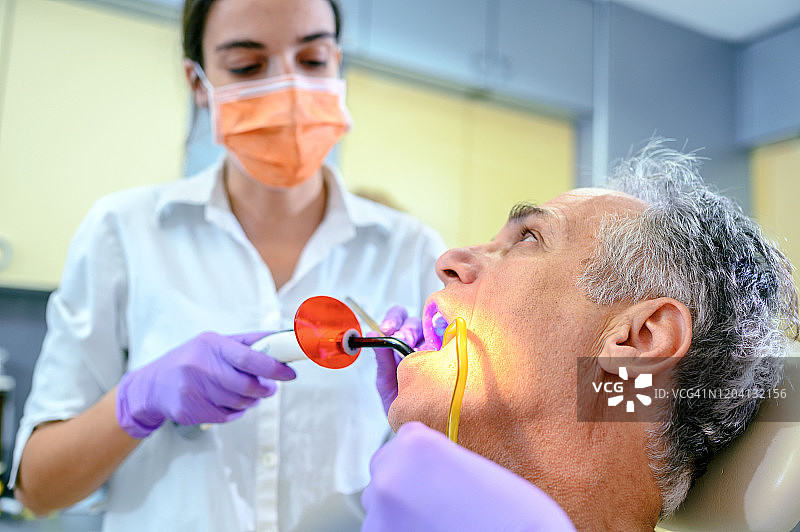 牙科医生使用紫外线灯治疗病人的牙齿图片素材