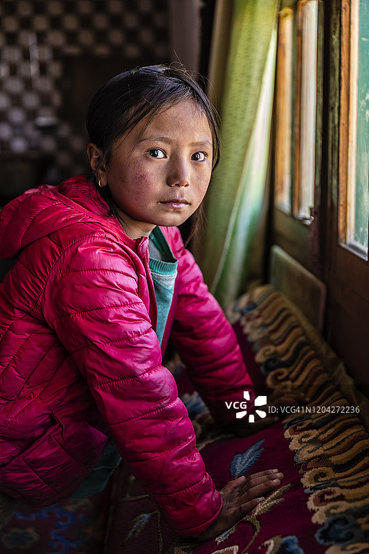 西藏小女孩透过窗户往外看，上野马，尼泊尔图片素材
