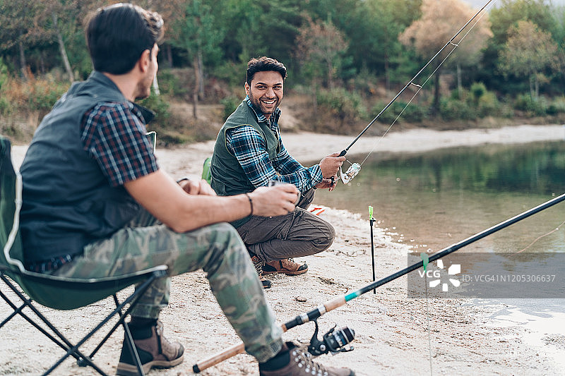 两个男人一边钓鱼一边聊天图片素材