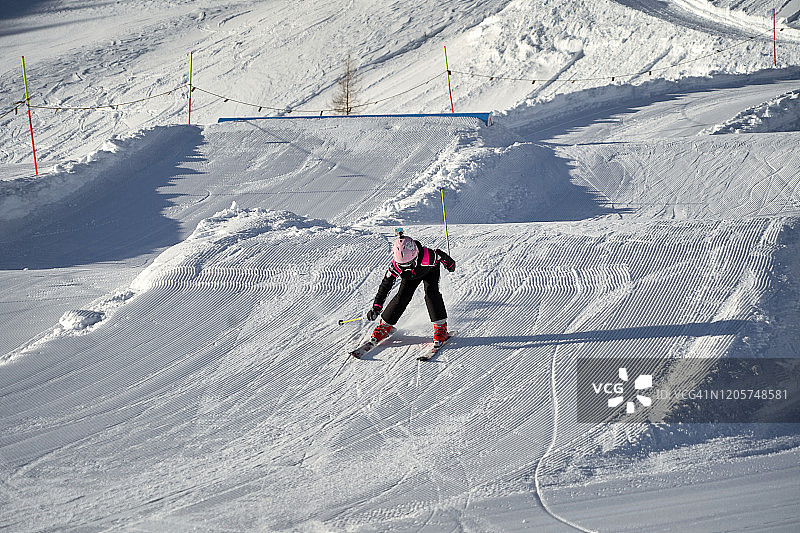 奥地利天空度假村，小女孩滑雪飞跃一个斜坡。图片素材