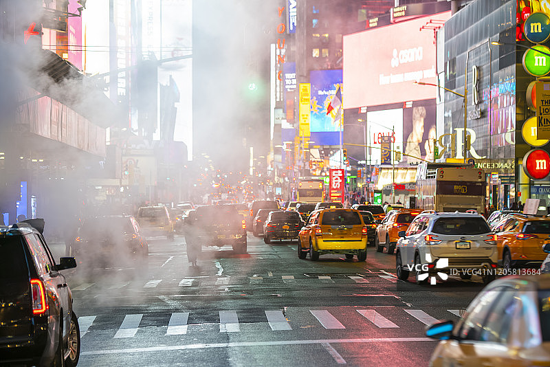 2020年1月14日，美国纽约，夜晚，人们穿过大道，曼哈顿中城的车流在漂浮的蒸汽中穿过时代广场。图片素材