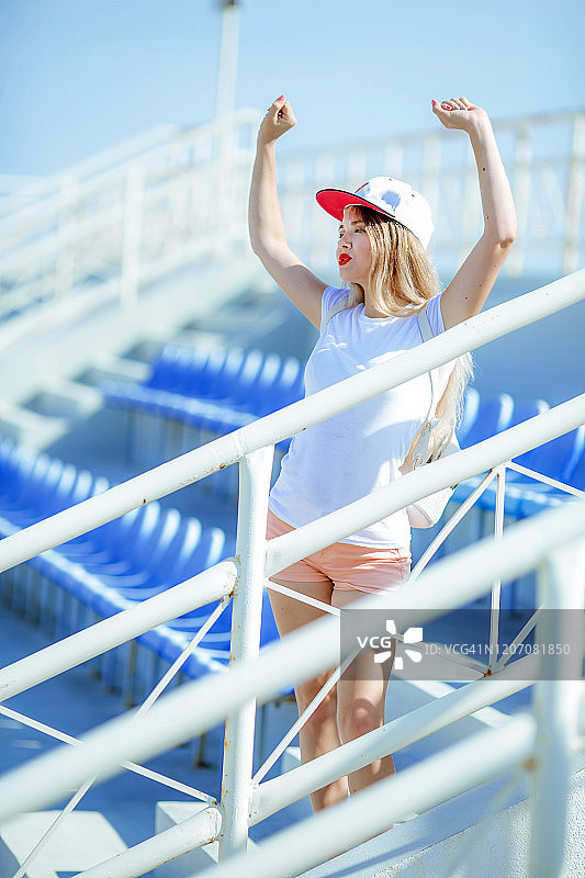 一名女子站在夏季体育领奖台上，穿着短裤，光着腿，头上戴着一顶帽子图片素材