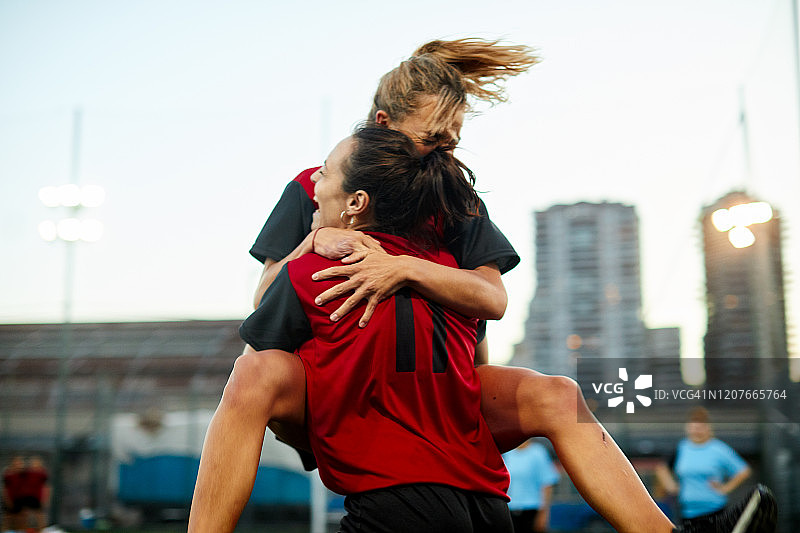 两名女子足球队队友在进球后拥抱庆祝。图片素材