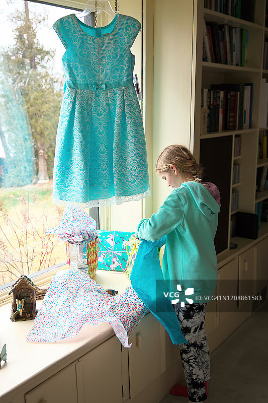 一个小女孩在大凸窗边打开礼物图片素材