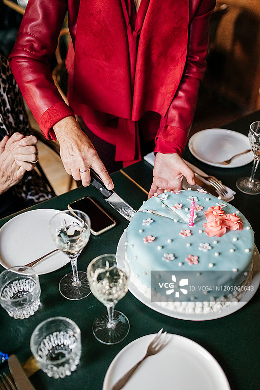 成熟的女人在餐厅切生日蛋糕图片素材
