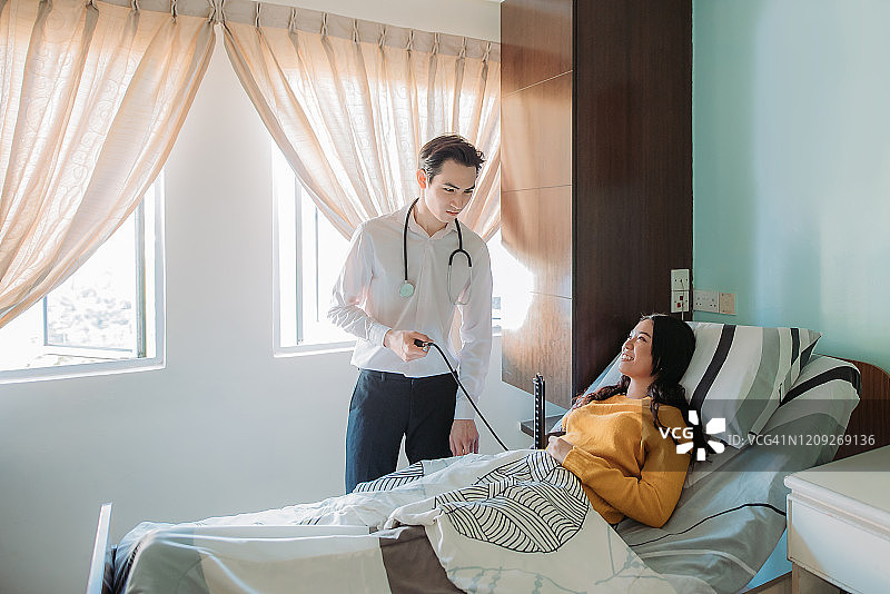 亚裔华裔男医生在医院为病人测量血压、心跳图片素材