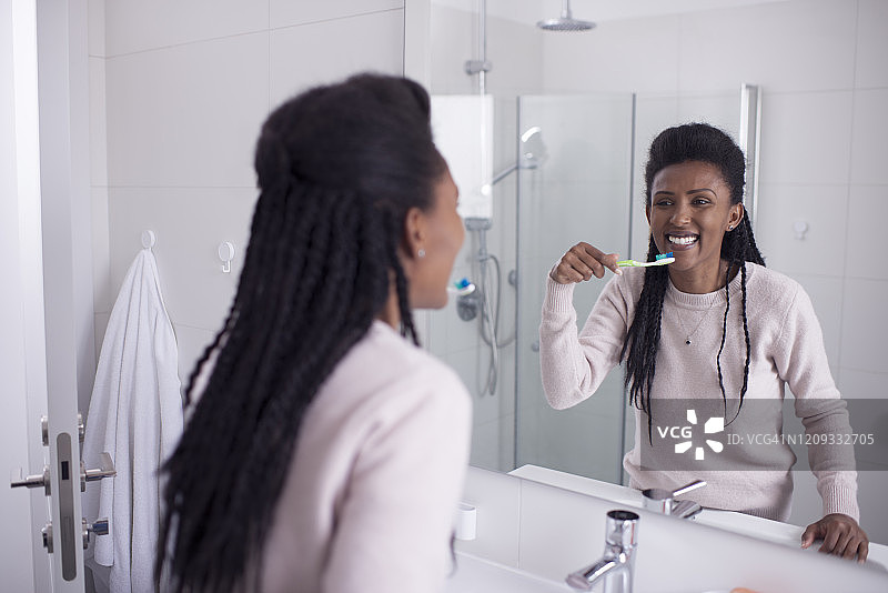 一个女人在浴室里刷牙。图片素材