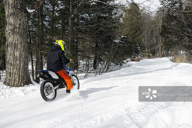一个十几岁的男孩在雪地里骑着他的越野自行车图片素材