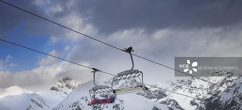阳光明媚的缆车，雪坡，冬季高山和黑暗多云的天空图片素材