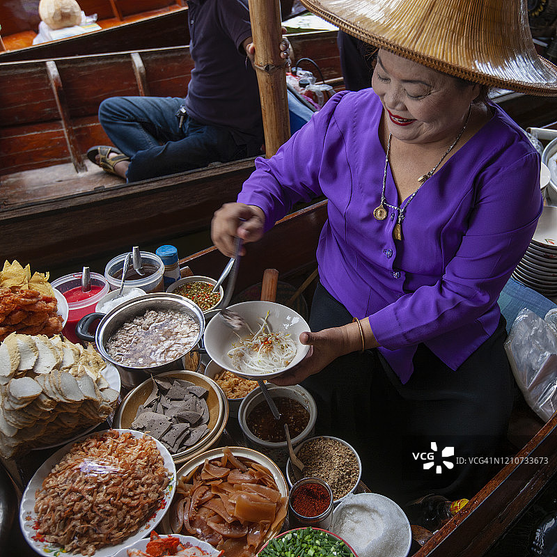 在Damnoen Saduak水上市场上，一名传统泰式面条小贩正在出售刚从运河船上买来的新鲜泰式面条汤。图片素材