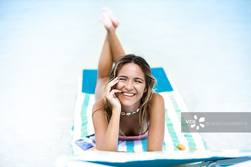 年轻快乐的女人在甲板上的椅子上享受夏日。图片素材