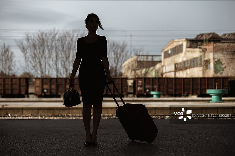 一个年轻女子在火车站拖着一个手提箱图片素材