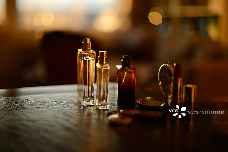 香水瓶，项链和化妆品在美丽的金色阳光下的黑色背景图片素材