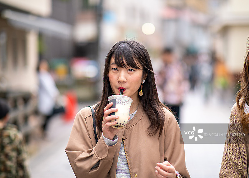年轻女子在街上喝着木薯茶图片素材