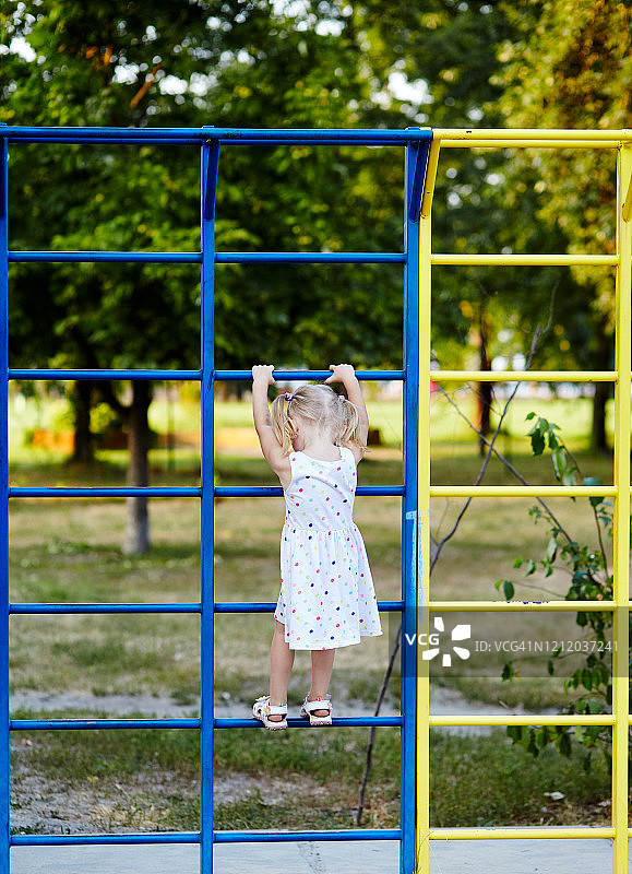 快乐微笑的小女孩在公园的户外操场上玩耍。女孩很开心。暑假或春假图片素材