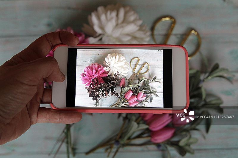 花商在社交媒体上用智能手机拍摄花圈。图片素材
