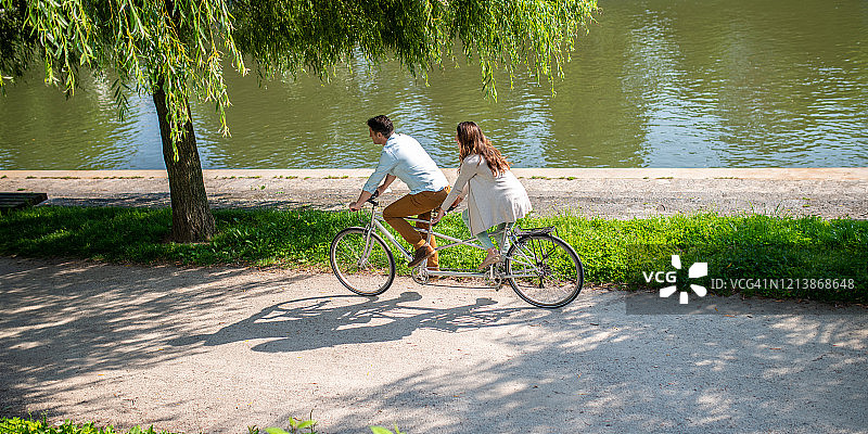 一对白人夫妇在河岸上骑双人自行车图片素材