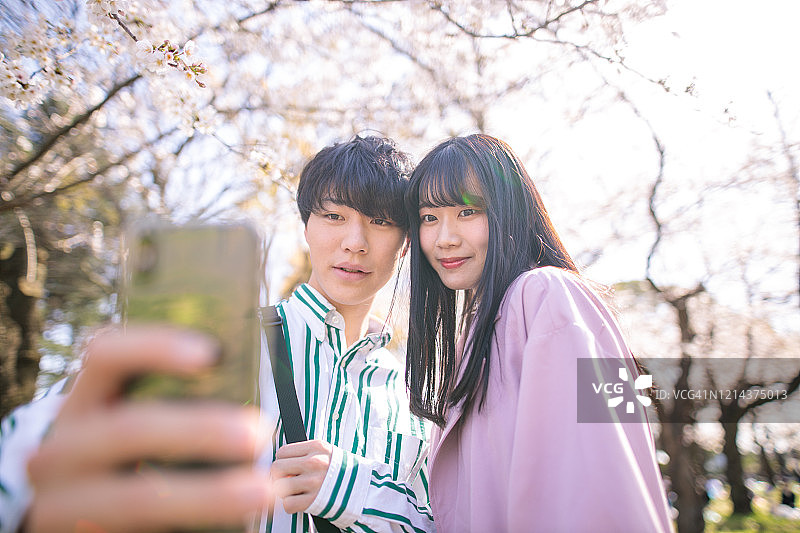 年轻夫妇在樱花下自拍图片素材