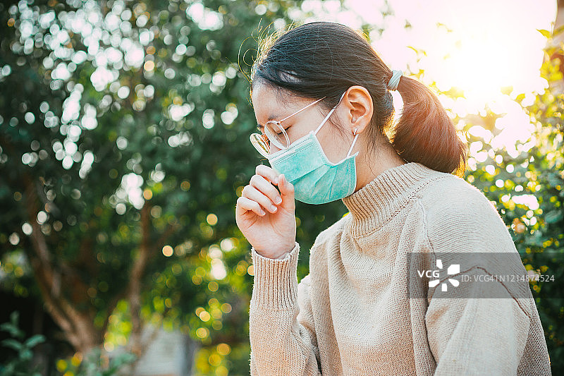 年轻的亚洲青少年戴上防护口罩以防止冠状病毒的传播，并搬到她的家里进行隔离。全球突发卫生事件Covid-19图片素材