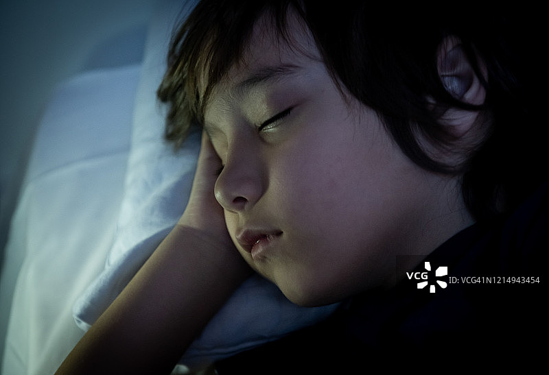 一个学龄前的小男孩在床上睡觉图片素材