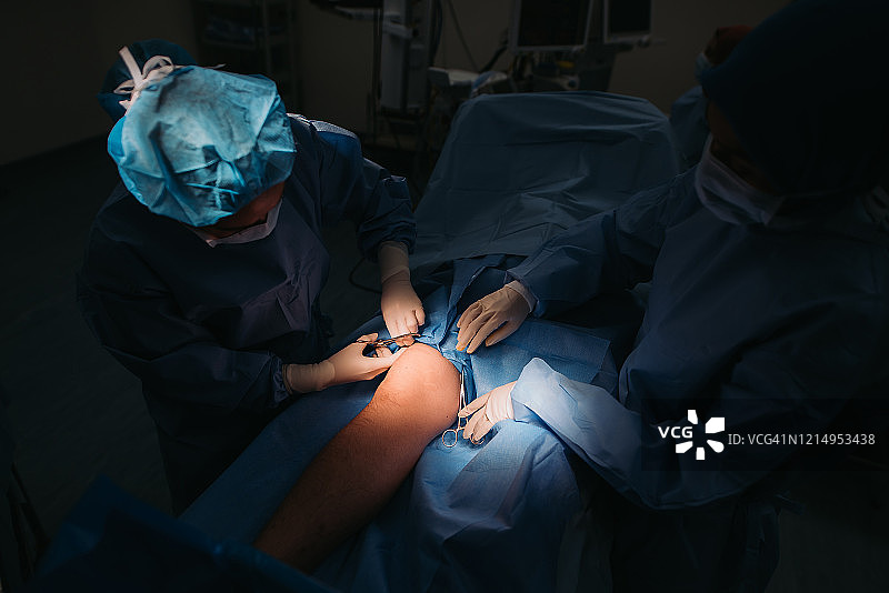 在医院的手术室里，亚洲多种族女性外科医生团队正在为一名亚洲华人男性做腿部手术图片素材