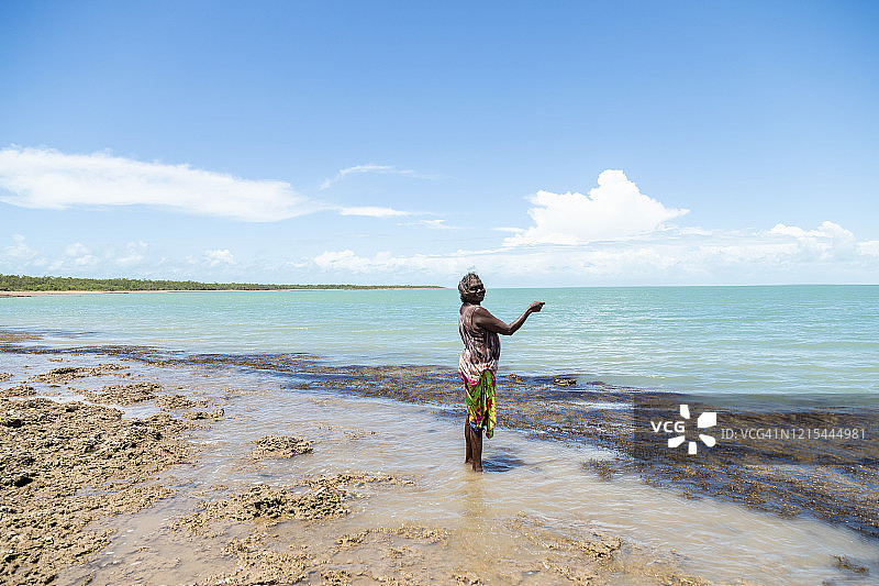 年长的土著妇女站在海边钓鱼图片素材