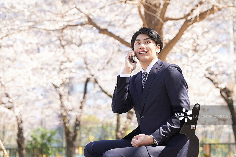 一位日本男性商人面带微笑地打来电话。图片素材