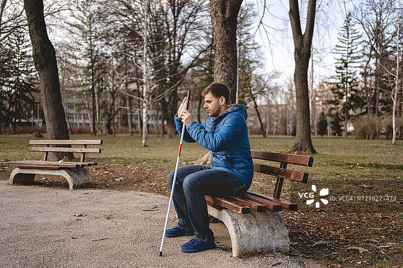 一个盲人坐在长椅上享受轻松的早晨图片素材