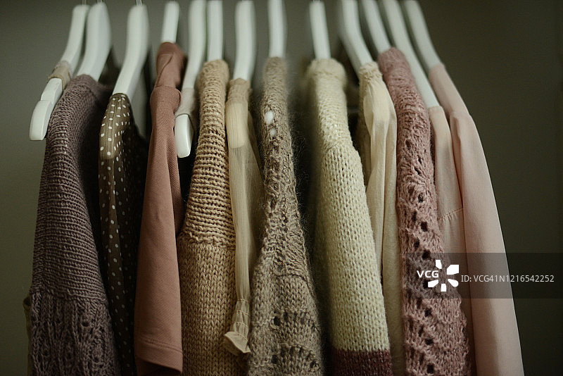 挂在衣架衣架上的淡粉色和棕色调的衬衫和毛衣图片素材