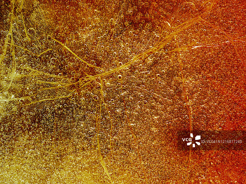完整的纹理框架由一块破裂的冰在橙色的背景上形成。图片素材