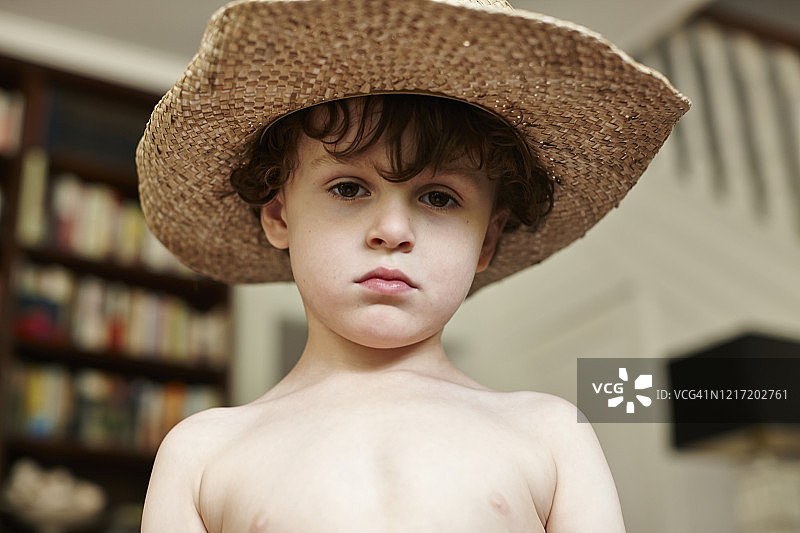 年幼的小男孩，棕色卷发，棕色眼睛，戴着牛仔帽看着镜头图片素材