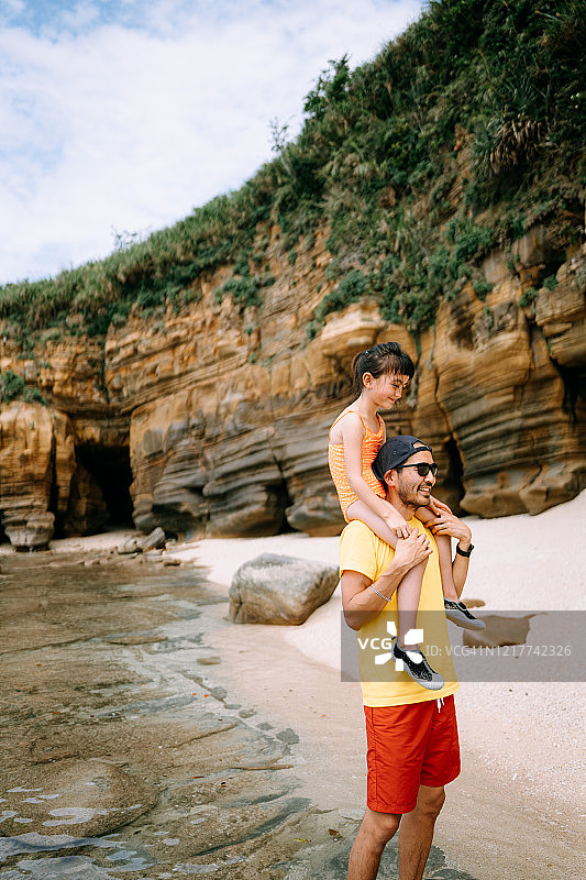 父亲背着小女孩在日本冲绳的海滩上图片素材