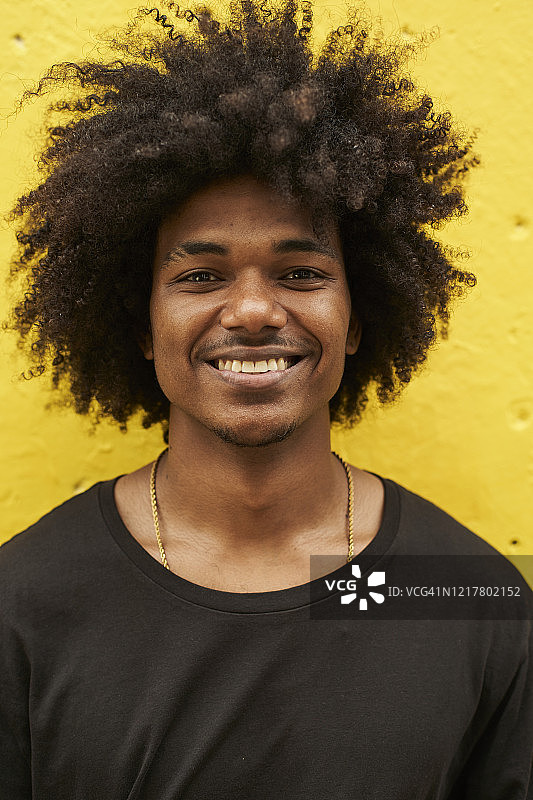 黄色墙上挂着一个快乐的年轻人的爆炸头图片素材