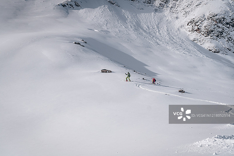 偏远地区的滑雪者穿过积雪的山坡图片素材
