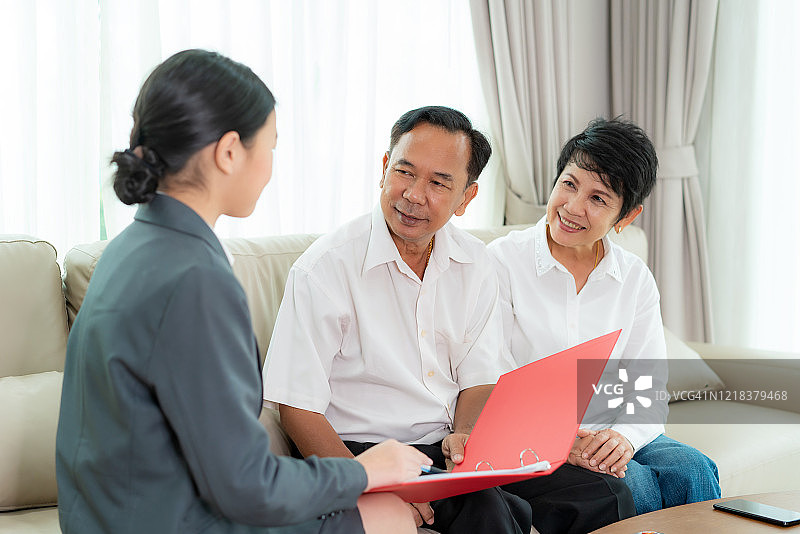 亚洲资深夫妇在家中接受专业理财人员提供的家庭理财或房地产保险或健康保险建议后，感到幸福愉快。图片素材