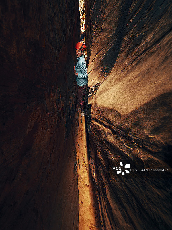 一名年轻女子奋力向上，穿过一条狭窄的峡谷图片素材