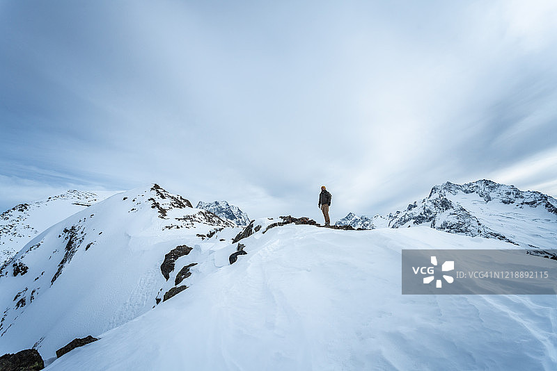 旅行者独自站在雪山之巅图片素材