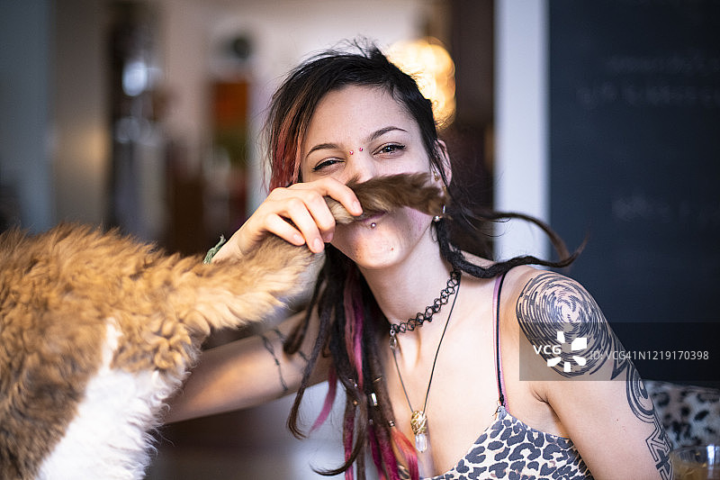 一个年轻的女人把猫的尾巴举到脸前，像蓄胡子一样图片素材
