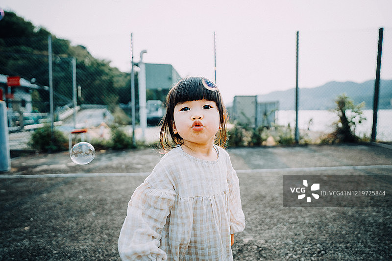 快乐微笑的亚洲女孩玩泡泡户外在公园里图片素材