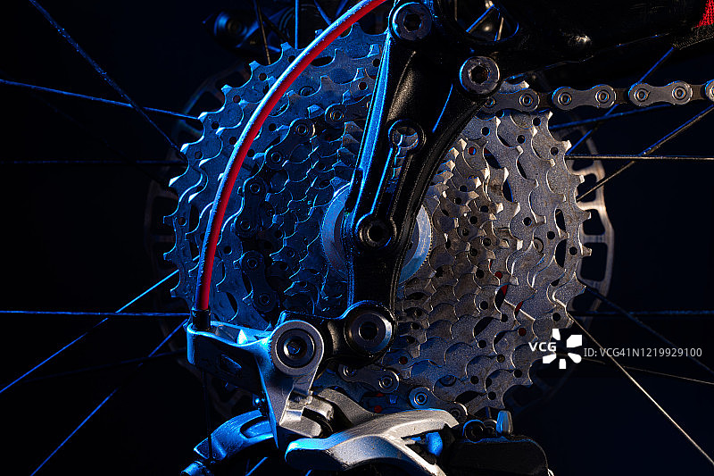 后方自行车齿轮与白色和蓝色的灯光在黑色的背景图片素材