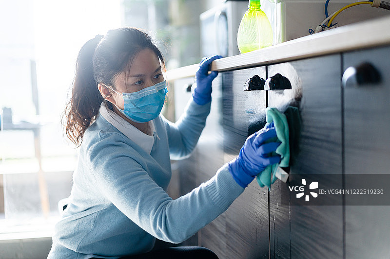 女性戴上防护面罩，用消毒液擦拭清洁家居图片素材