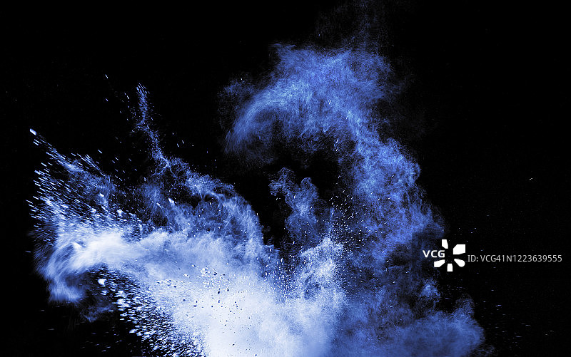 由白色和蓝色的粉末颗粒云在黑色背景上的冲击而产生的爆炸。图片素材